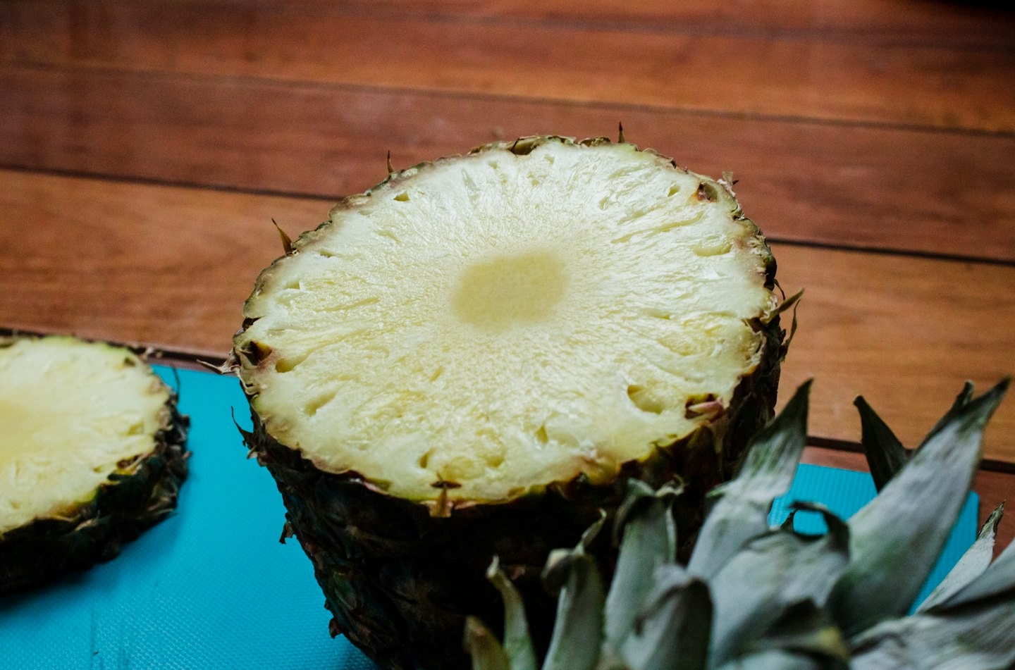 A sliced pineapple rests on a turquoise cutting board.